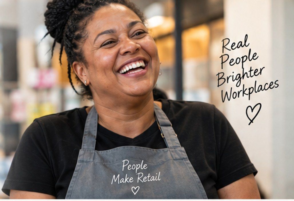 Temporary mock-up image: a laughing retail worker in an apron in a shop.